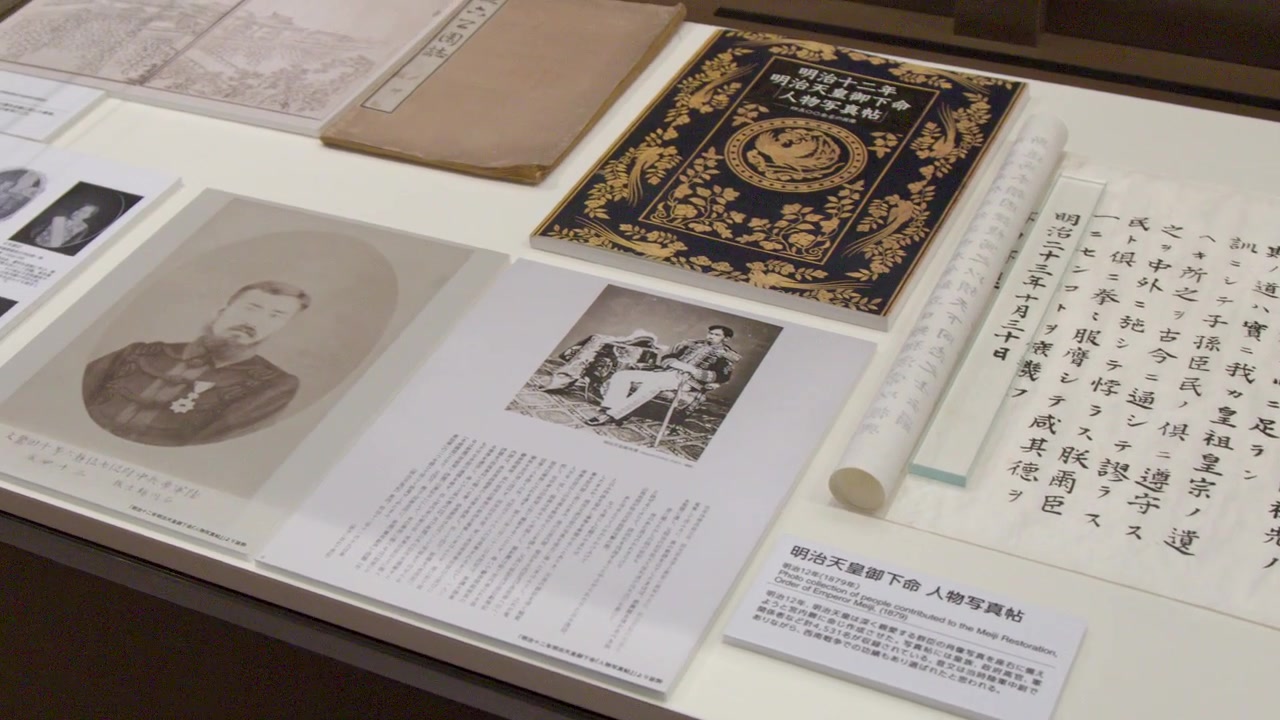 鏡頭緩慢推近，展示博物館展櫃內歷史悠久的日本文獻、卷軸和書法。
