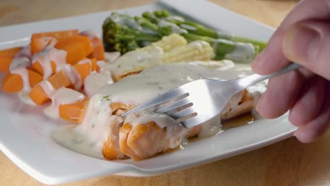cerrar toma en cámara lenta de comer un trozo de filete de salmón frito y salsa blanca con un tenedor