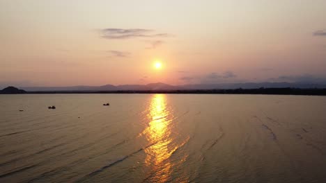 AERIAL:-Drone-Descends-above-the-bay-on-the-sunset-with-mountains-on-the-background-in-Southern-Thailand,-Asia