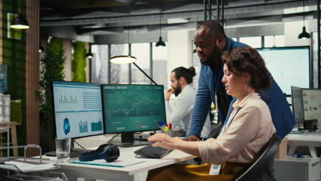 vertical video diverse office coworkers reviewing monthly data graphs to create reports