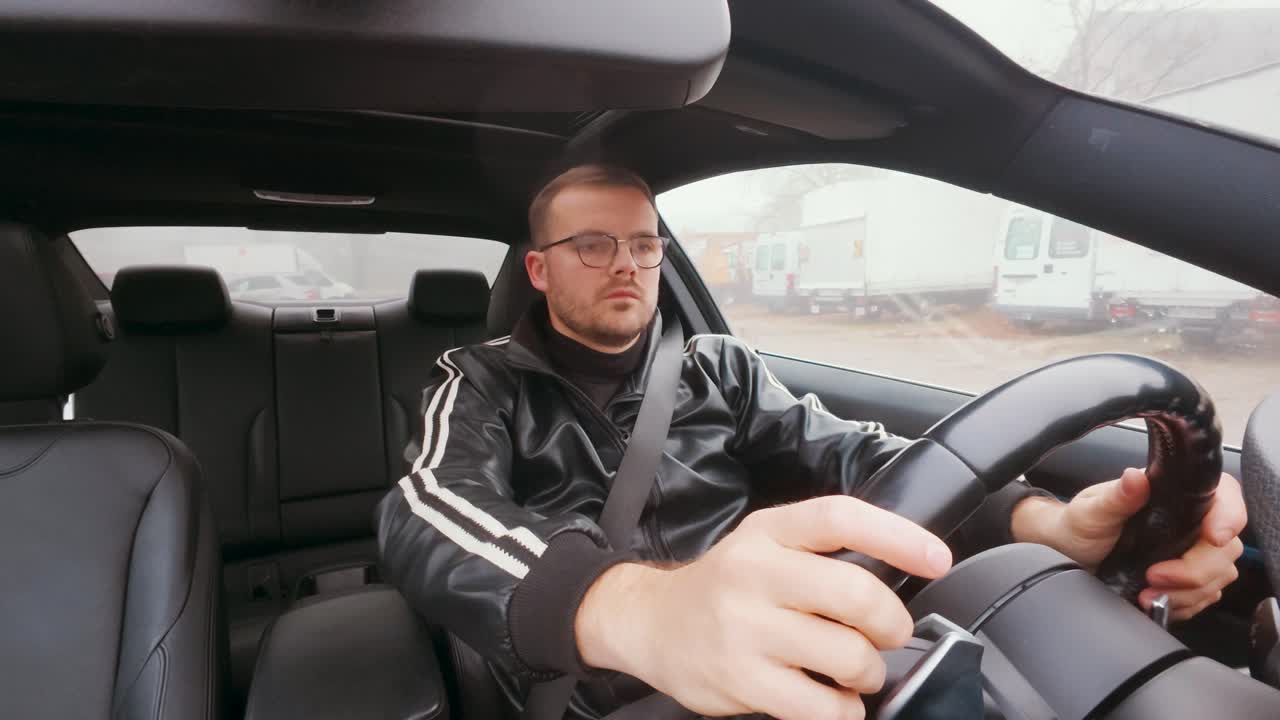 Un hombre en un coche se abrocha el cinturón de seguridad, comprueba que le quede bien, mira por encima del hombro para comprobar el ángulo muerto y luego se marcha, girando con seguridad. Concepto de seguridad vial y conducción responsable.