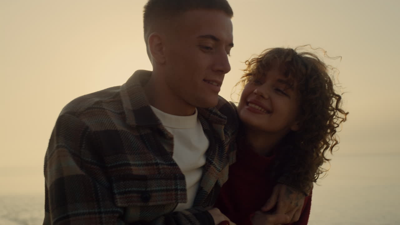 un hombre encantador abrazando a una mujer en la playa al atardecer. una pareja feliz caminando por la playa