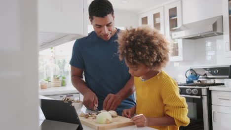 Padre-Mostrando-A-Su-Hija-Preadolescente-Cómo-Preparar-Comida-En-La-Cocina,-De-Cerca,-En-ángulo-Bajo