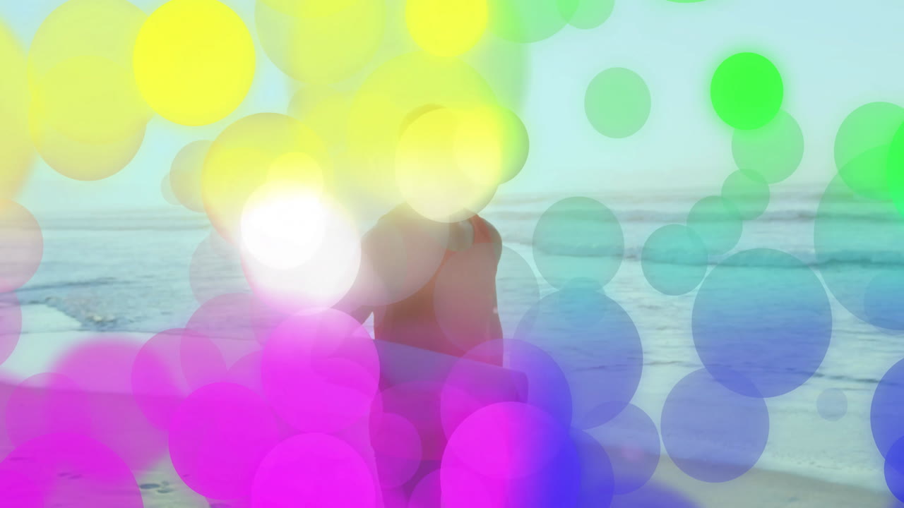 Person carrying surfboard on beach with colorful bubble animation overlay