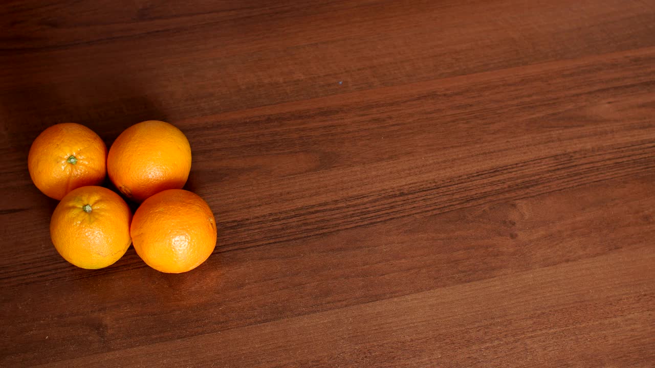 cuatro naranjas maduras y jugosas en una superficie de madera marrón.