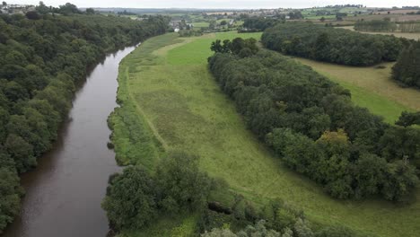 Toma-De-Drones-De-Un-Gran-Río-Que-Fluye-A-Través-De-Campos-Verdes