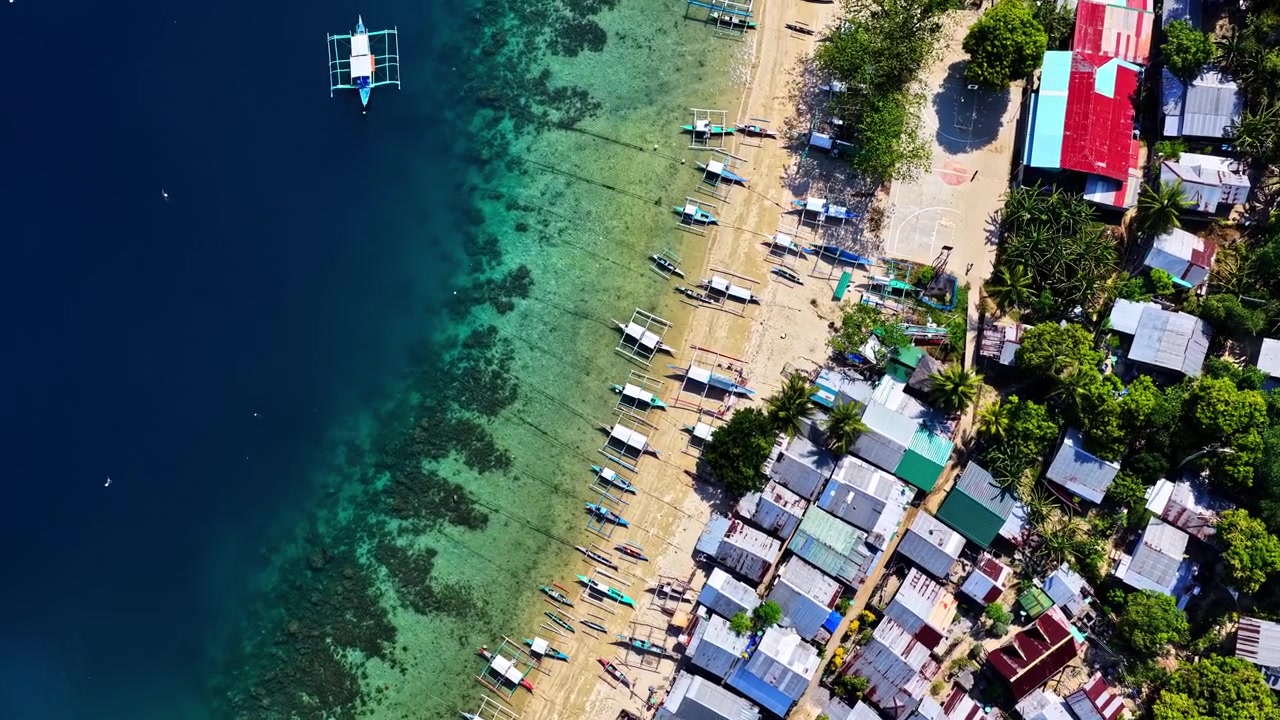 Vista dall'alto di un villaggio costiero tropicale con acqua cristallina.