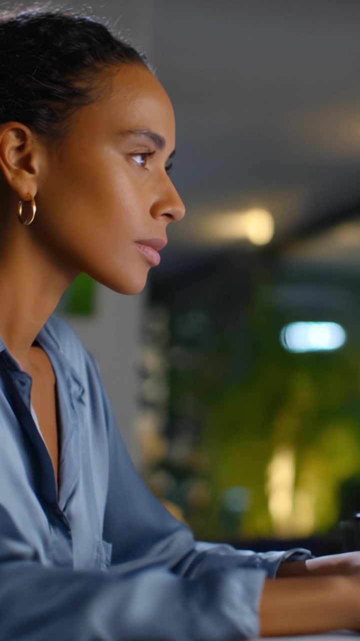 Focused Woman Engaged in Work While Using a Computer in a Modern Indoor Setting with Soft Lighting Reflecting Concentration and Professionalism