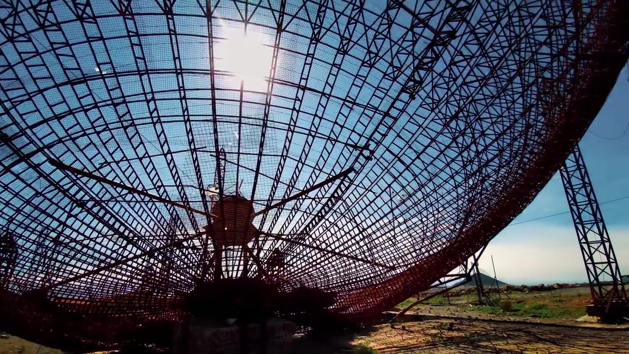Panoramica dietro una vecchia antenna parabolica per comunicazioni satellitari.