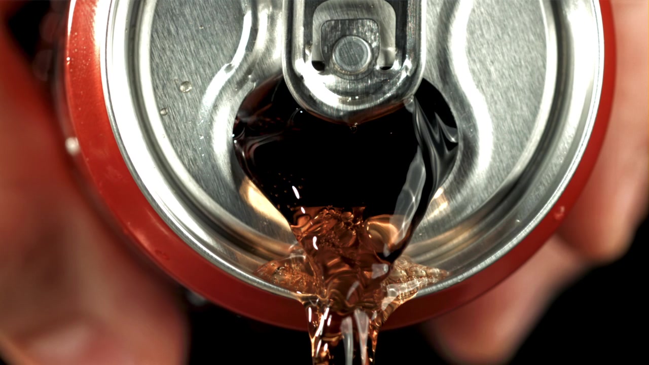 Primo piano di cola che si versa da una lattina rossa