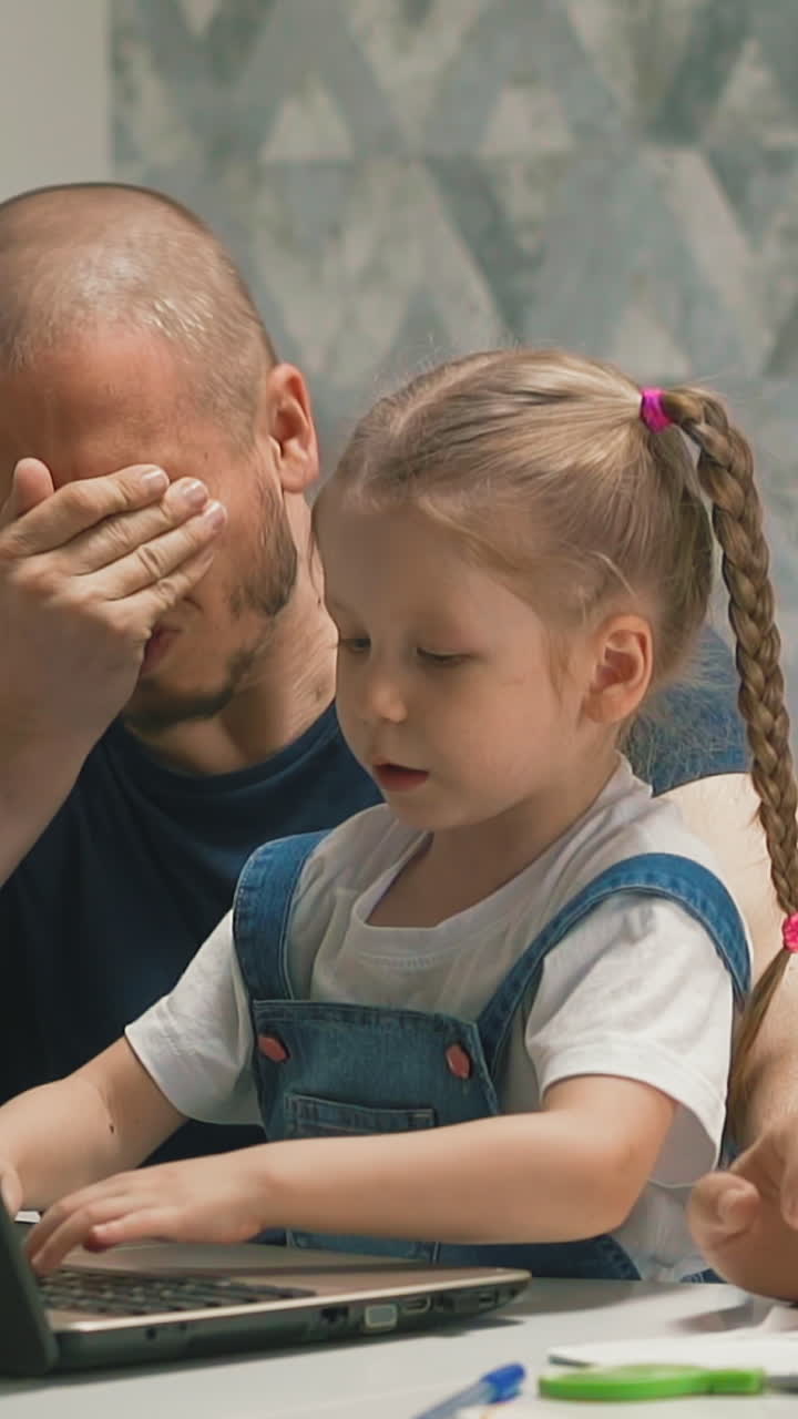 closeup slow motion father helps little child student to do lessons, at home to learn, grabs face, tired, daughter continues to work, on table lie books, notebooks, school supplies