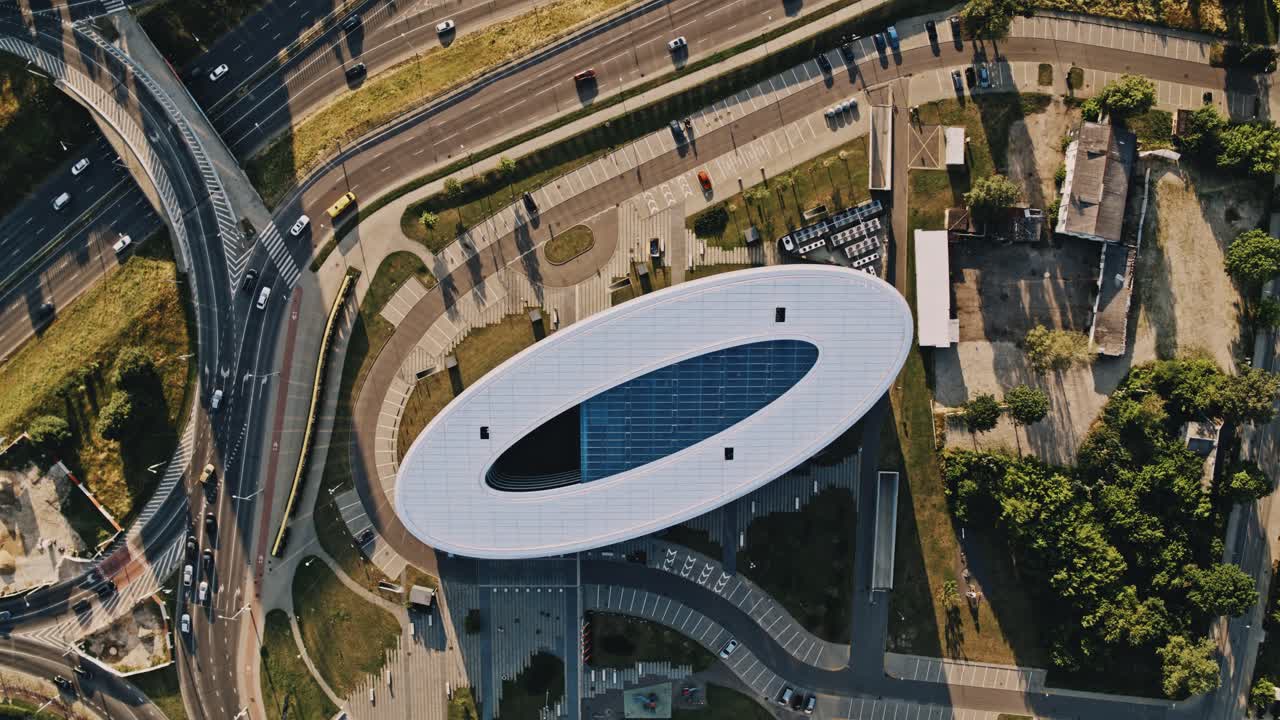 Oval shape building named K29 in Vilnius, Europe, Baltic states. Approaching drone camera view from high above the building. Streets, cars, people and traffic also visible in day time. Zenmuse X7.