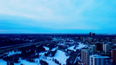 winter aerial fly over the recreational park for cross country skiing skating and sledding from a repurposed summer use of golfing and team activities of baseball softball at the rivers of dt edmonton