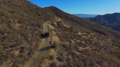 red jeep traveling on winding mountainside road on sunny day