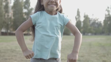 Portrait-of-a-cute-Latin-girl-smiling-at-the-camera-while-jumping-and-blowing-kiss-in-the-park