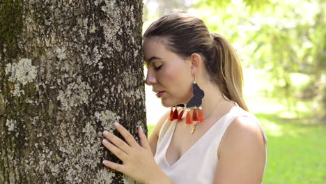 Close up of girl hugs and touches a tree while meditates and pray in the forest
