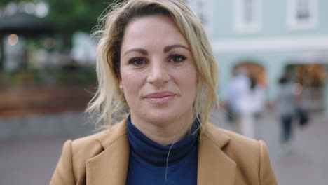 slow motion portrait of stylish blonde business woman in suit smiling pensive thoughtful at camera urban background