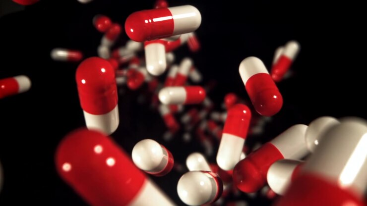 Red and White Capsules Falling in Slow Motion on Black Background