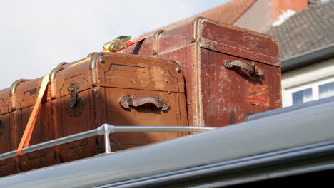 2 old vintage suitcases fastened together on top of an oldtimer bus coach