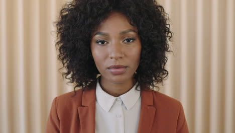 close-up-portrait-of-stylish-young-african-american-woman-afro-hairstyle-looking-serious-at-camera-trendy-black-female-wearing-suit