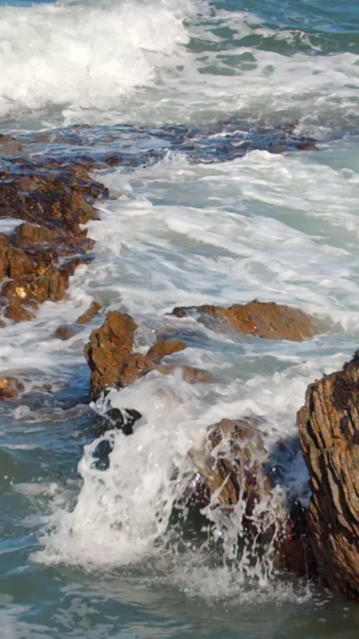Video ravvicinato in formato verticale per i social media di onde impetuose che si infrangono sugli scogli. Filmato in 1080x1920 e con colore Rec709