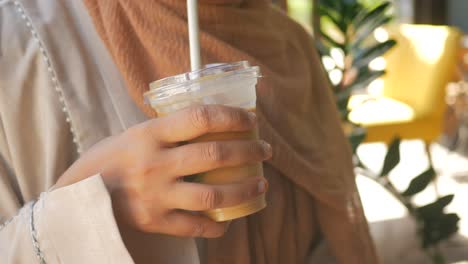 mujer sosteniendo café helado en un café
