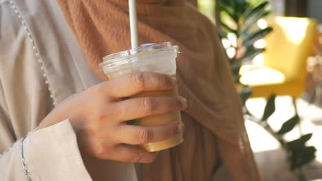 woman holding iced coffee in a cafe