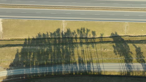 aerial top down - shadows of trees cast over a highwa