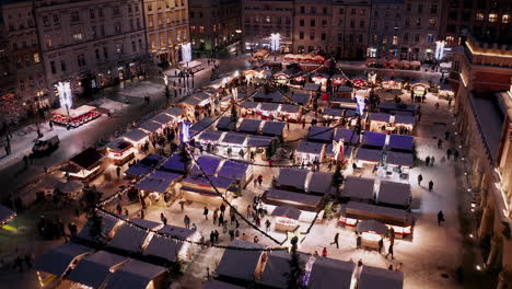 christmas stalls with snow at night on the main market square in krakow, poland