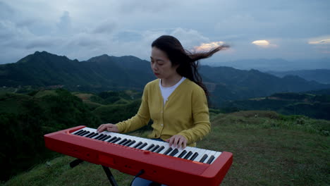 a woman playing the piano in the mountains under an overcast sky