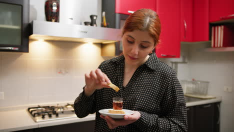 in a kitchen a woman tastes the cantucci she prepared
