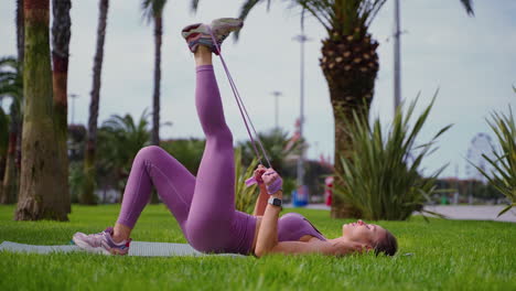 mujer haciendo levantamientos de piernas con banda de resistencia en un parque