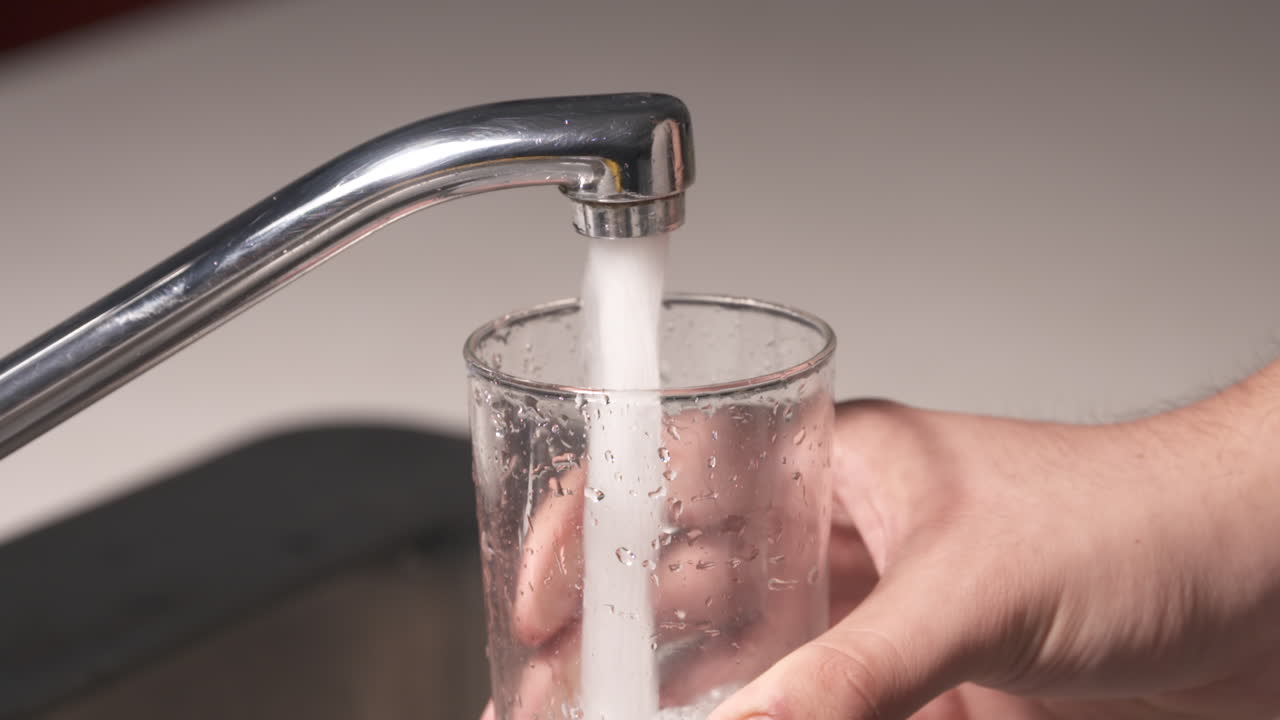 se abre un grifo de agua y se llena un vaso de agua