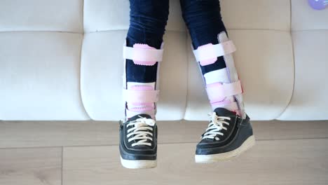 a young girl with a broken leg in a cast sitting on a white couch