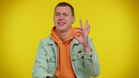 Teen-stylish-man-looking-approvingly-at-camera-showing-ok-gesture-like-sign-positive-something-good