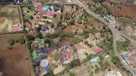 Aerial-view-of-a-town-and-sunlit-fields,-golden-hour-in-rural-Africa---tracking,-drone-shot