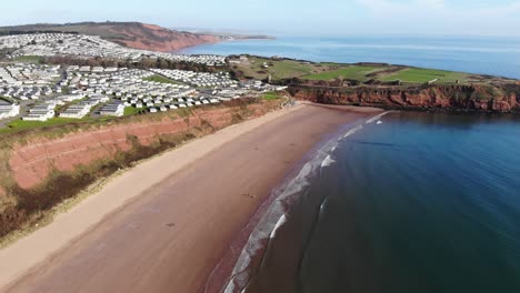 Aerial-Over-Sandy-Bay-Beach-With-Holiday-Park-Overlooking