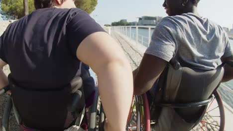 rear view of happy couple with disability wheeling and talking