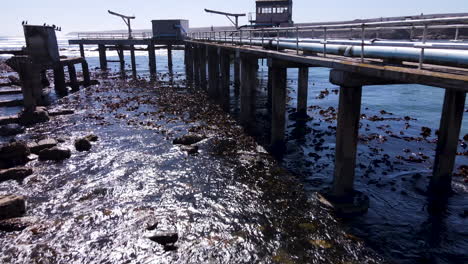 Drone flight over old decrepit jetty structure on atlantic ocean coastline