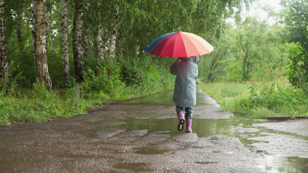 A little girl walks through a puddle in the rain
