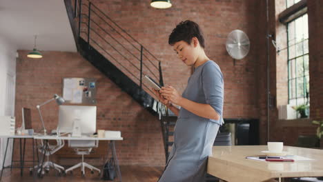 Stylish-Asian-Business-woman-using-digital-tablet-in-boardroom