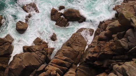aerial view of waves crashing on a rocky coastline