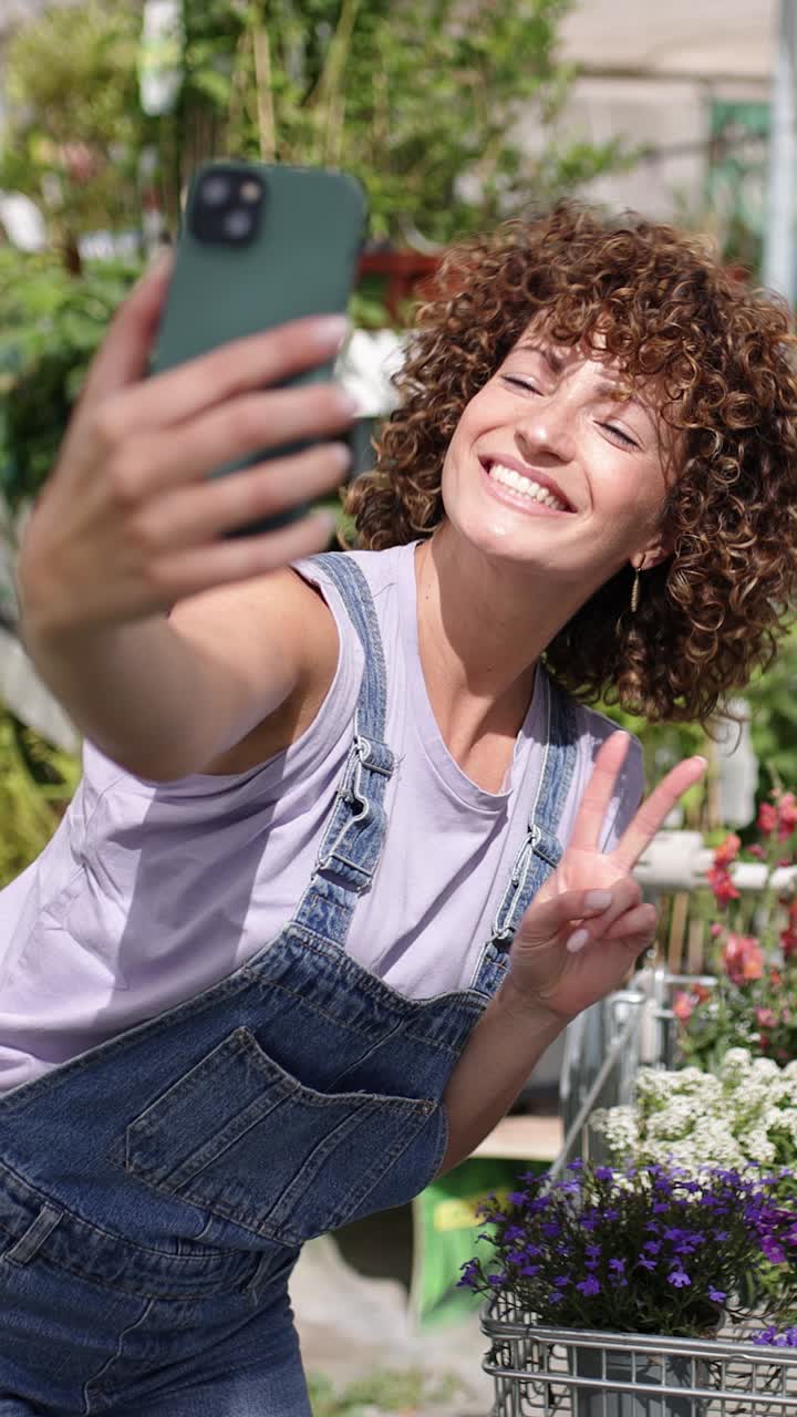 Gardener taking selfies with flowers in garden center. Vertical
