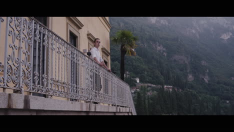 man on balcony overlooking a scenic lake view