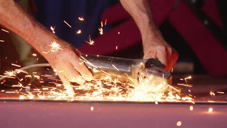 close up tradesman using power tool to grind bolt, causing sparks, 4k slow motion