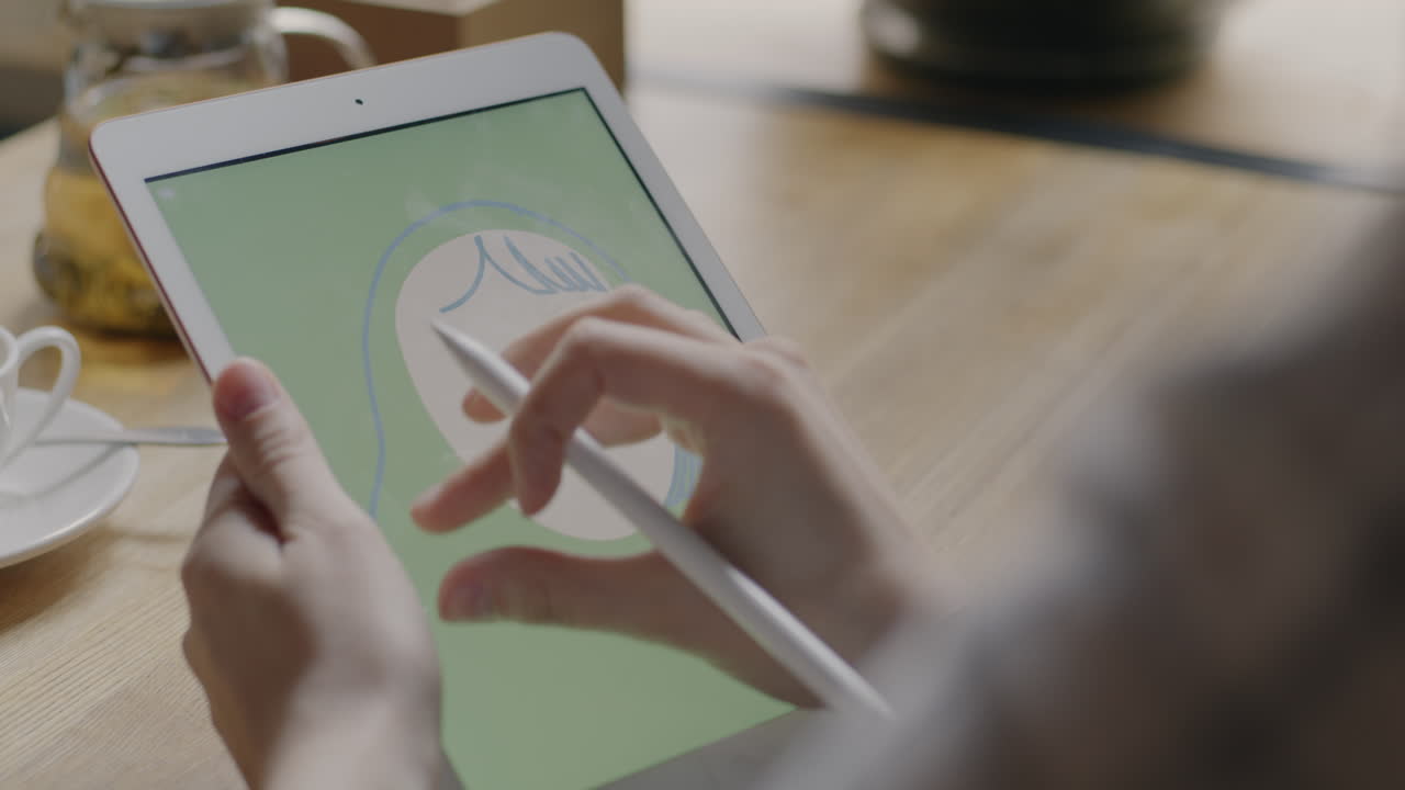 Person Drawing on Tablet in Cafe