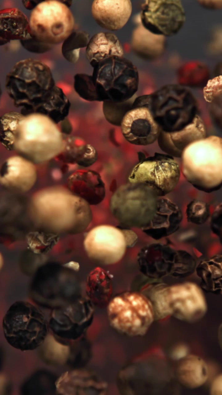 Assorted Peppercorns and Red Spice Flakes Falling in Slow Motion