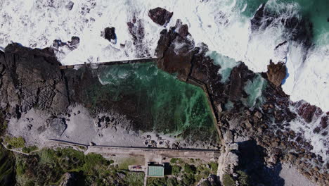 Olas-Rompiendo-Junto-A-La-Icónica-Piscina-De-Mareas-Marinas-En-Hermanus,-Lapso-De-Tiempo-De-Drones