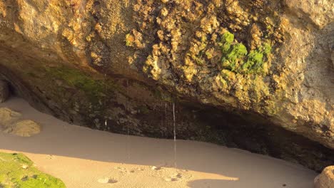 Water-cascades-from-rocky-structures,-showering-droplets-upon-the-stony-surface