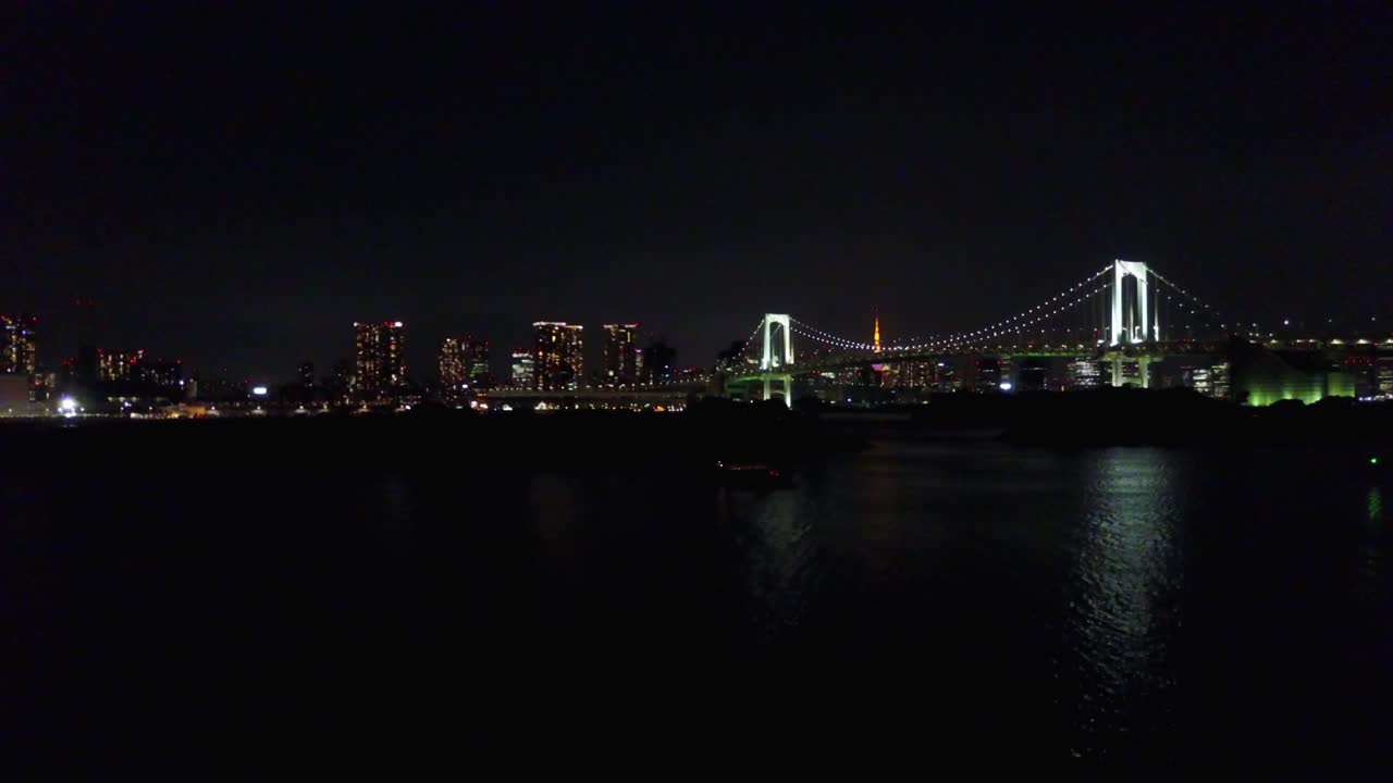 밤 시간에 물 위에 무지개 다리 위로 떠오르는